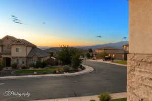 View of asphalt road featuring sidewalks, curbs, a mountain view, a residential view, and traffic signs