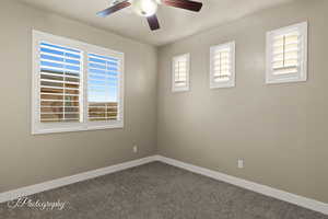 Carpeted empty room featuring a ceiling fan and baseboards