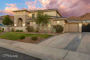 View of front of home featuring stucco siding, concrete driveway, stone siding, and an attached garage