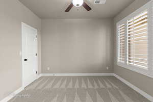 Carpeted empty room featuring a ceiling fan and baseboards