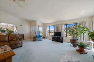Living room featuring ceiling fan, carpet floors, and lofted ceiling