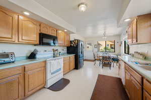 Kitchen with white appliances, light countertops, a ceiling fan, and recessed lighting