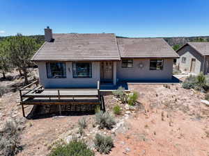 Back of house with a chimney, stucco siding, and a tile roof
