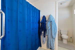 Full bath featuring toilet and marble look tiles