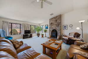 Living area featuring vaulted ceiling, carpet, a wood stove, and ceiling fan