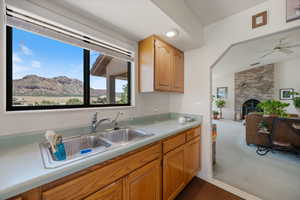 Kitchen featuring dark colored carpet, light countertops, a ceiling fan, a fireplace, and open floor plan