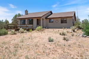 View of front facade featuring a chimney, a tiled roof, stucco siding, and a deck
