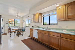Kitchen featuring light countertops, a ceiling fan, brown cabinetry, and freestanding refrigerator