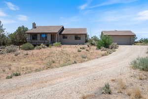 Single story home featuring driveway, a chimney, a garage, stucco siding, and a wooden deck