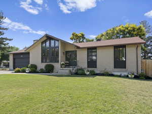 Mid-century inspired home featuring brick siding, a garage, a chimney, driveway, and roof with shingles
