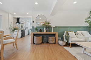 Interior space featuring light wood-type flooring, recessed lighting, a decorative wall, and wainscoting