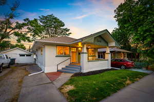 View of front of property with driveway, brick siding, a detached garage, covered porch, and an outdoor structure