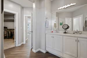 Bathroom with double vanity, wood finished floors, and a walk in closet