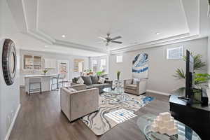 Living room with a tray ceiling, dark wood finished floors, ceiling fan, healthy amount of natural light, and recessed lighting