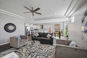Living area featuring wood finished floors, a ceiling fan, recessed lighting, and a tray ceiling