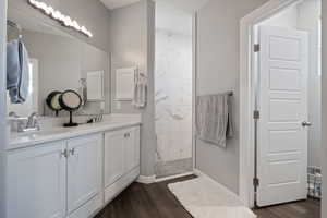 Bathroom featuring wood finished floors, a walk in shower, and double vanity