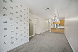 Unfurnished living room featuring arched walkways and light colored carpet