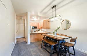 Dining area featuring dark colored carpet and baseboards