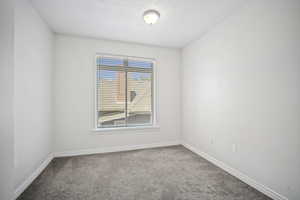 Carpeted second bedroom featuring baseboards and a textured ceiling