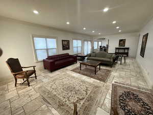 Living room with ornamental molding, stone tile flooring, recessed lighting, and arched walkways