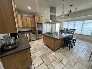 Kitchen featuring island range hood, appliances with stainless steel finishes, ornamental molding, a kitchen bar, and arched walkways