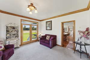 Carpeted living room featuring french doors and crown molding