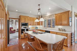 Kitchen featuring oven, black dishwasher, light countertops, a kitchen breakfast bar, and recessed lighting