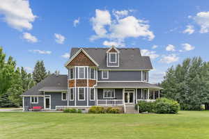 Back of property with a porch, a yard, and roof with shingles