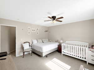 Carpeted bedroom with a ceiling fan and baseboards