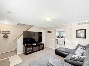 Living room with light colored carpet, stairs, and crown molding