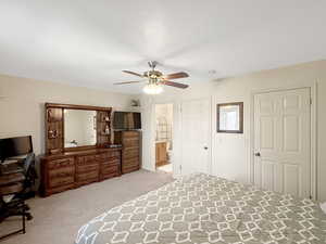 Bedroom with carpet floors, ceiling fan, and connected bathroom