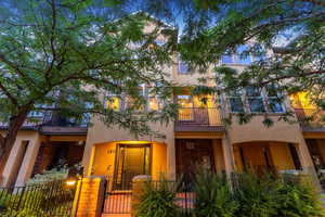 View of front of house featuring a balcony, stucco siding, a fenced front yard, and a gate