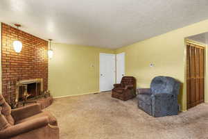 Carpeted living room featuring a fireplace and a textured ceiling
