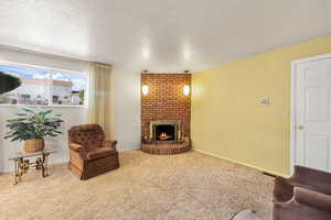 Living room featuring carpet flooring, a brick fireplace, and a textured ceiling