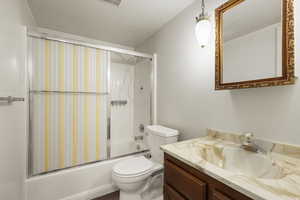 Full bath featuring vanity, enclosed tub / shower combo, and a textured ceiling