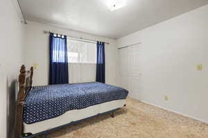 Bedroom featuring a closet, a textured ceiling, and carpet floors