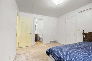Carpeted bedroom with a textured ceiling and connected bathroom