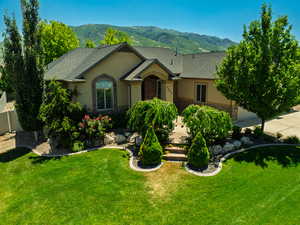 View of front of home featuring stucco siding, a mountain view, stone siding, and a shingled roof