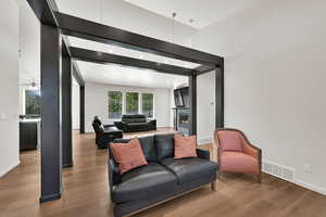 Living area with wood finished floors, a lit fireplace, a high ceiling, and a ceiling fan