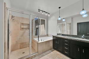 Full bath featuring double vanity, a garden tub, a shower stall, and tile patterned floors