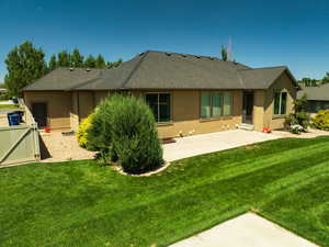 Rear view of house with stucco siding, a patio area, and roof with shingles