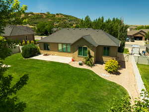 Back of house featuring roof with shingles, stucco siding, a patio, a fenced backyard, and a gate