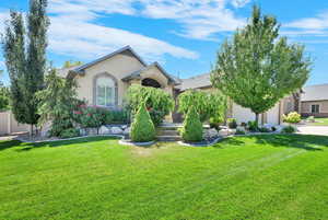 View of front of home featuring stucco siding, a front yard, concrete driveway, and a garage