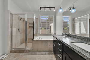 Bathroom featuring a bath, double vanity, and a stall shower