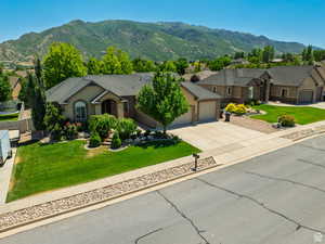 Single story home featuring a front lawn, concrete driveway, a mountain view, an attached garage, and roof with shingles