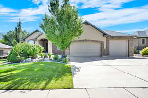 View of front of property featuring an attached garage, driveway, a front lawn, and stucco siding