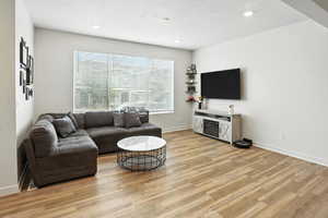 Living area with new light wood-style LVP floors and recessed lighting