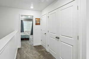 Hallway featuring dark carpet