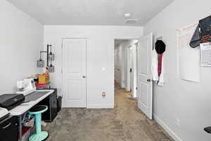 Bedroom used as office space featuring carpet floors and a textured ceiling