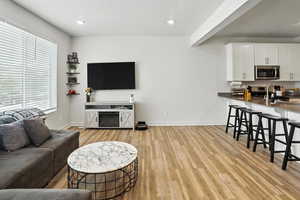 Living area with brand new light wood-style LVP flooring and recessed lighting